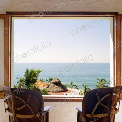 Empty chairs facing open window overlooking ocean Empty chairs facing open window overlooking ocean