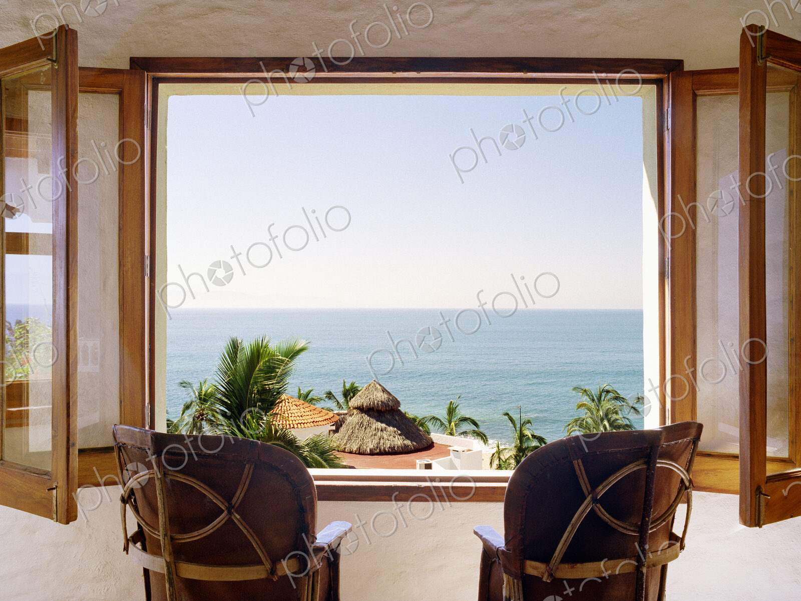 Empty chairs facing open window overlooking ocean