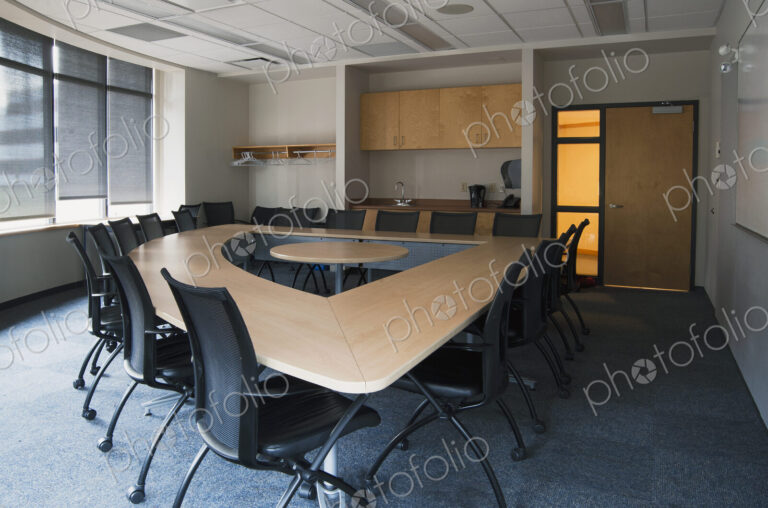 Empty meeting room in an office with triangular shaped table with a central space.