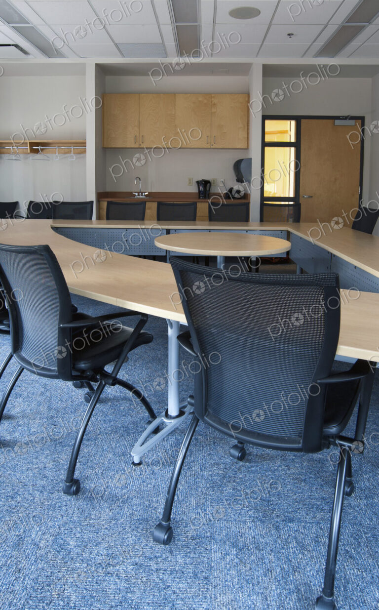 Empty meeting room in an office with triangular shaped table with a central space.