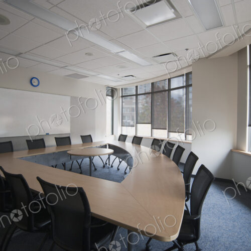 Empty meeting room in an office. A triangular shaped table with a central space. A…