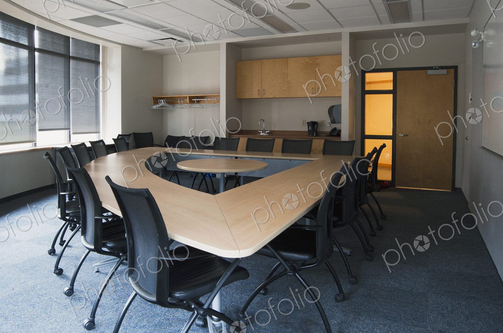 Empty meeting room in an office. A triangular shaped table with a central space. Door…