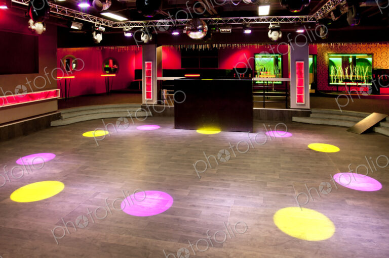 Empty nightclub, coloured lights and spots, screens and DJ decks.
