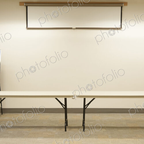 Empty tables under projector screen in classroom Empty tables under projector screen in classroom