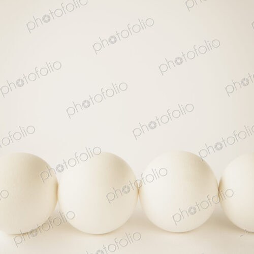 End-on view of free range, organic eggs with white shells arranged in a row, on a… End-on view of free range, organic eggs with white shells arranged in a row, on a…