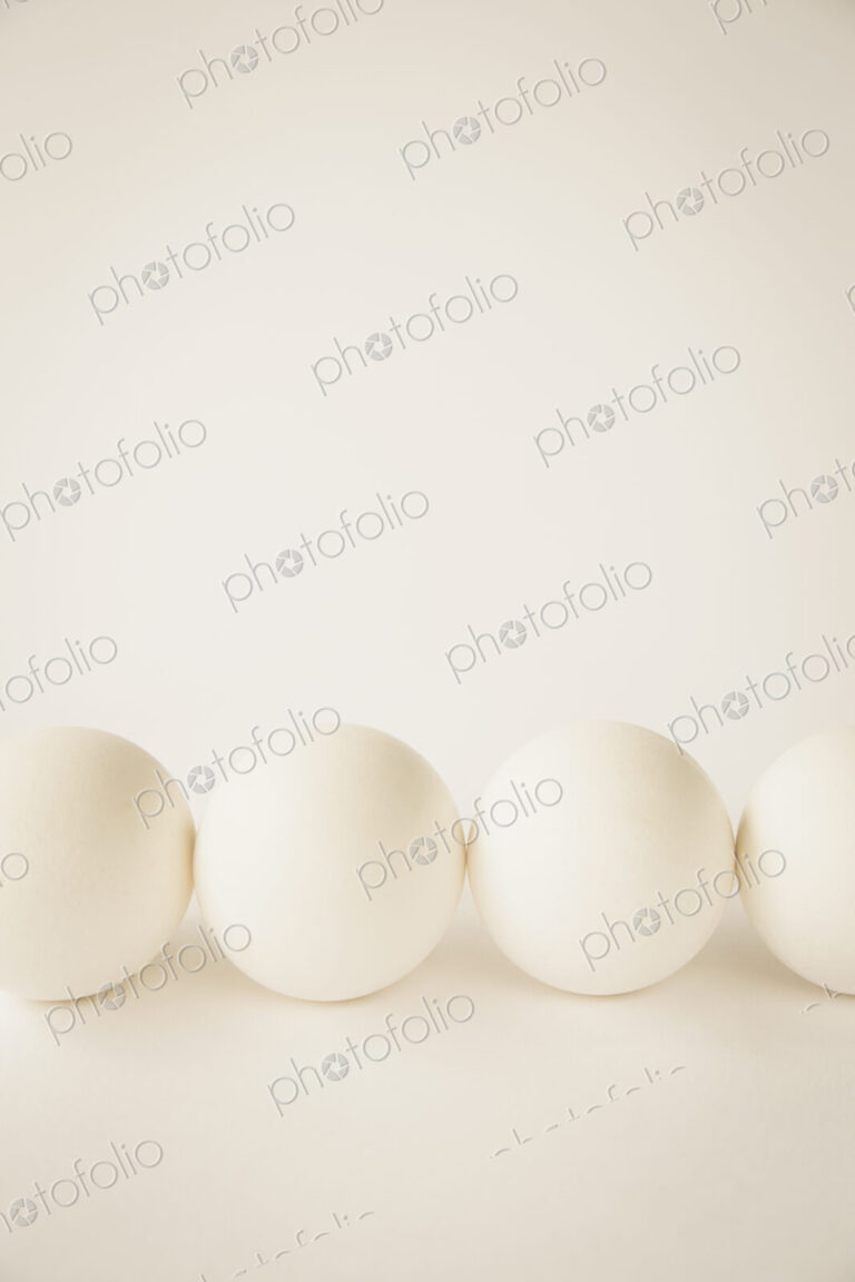 End-on view of free range, organic eggs with white shells arranged in a row, on a…