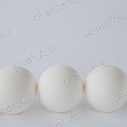End-on view of free range, organic eggs with white shells arranged in a row, on a… End-on view of free range, organic eggs with white shells arranged in a row, on a…