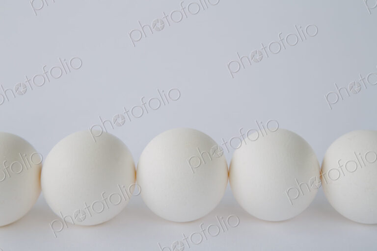 End-on view of free range, organic eggs with white shells arranged in a row, on a…
