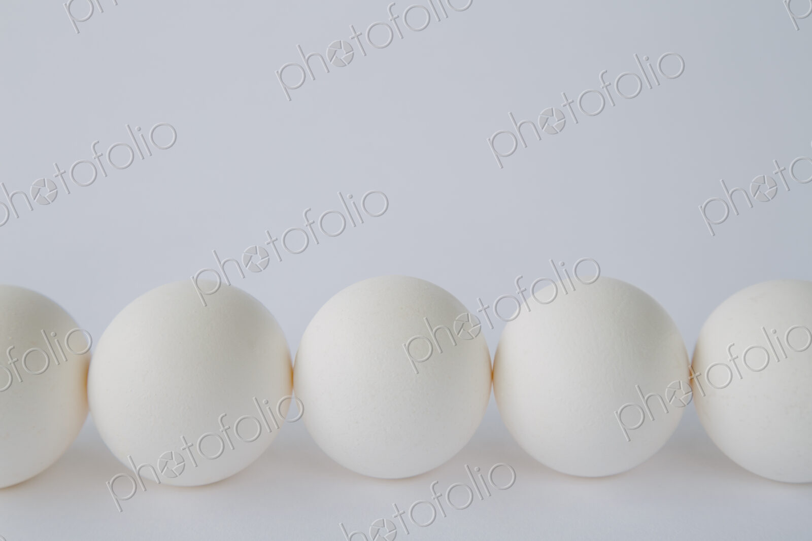 End-on view of free range, organic eggs with white shells arranged in a row, on a…