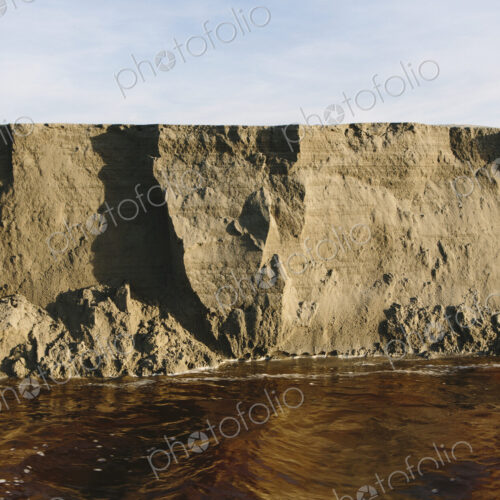 Eroding sand cliffs and fast moving water along intertidal area. Eroding sand cliffs and fast moving water along intertidal area.
