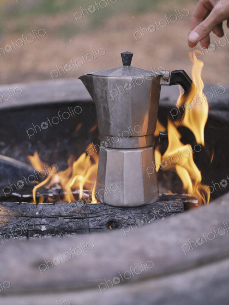 Espresso maker standing over an outdoor fire.