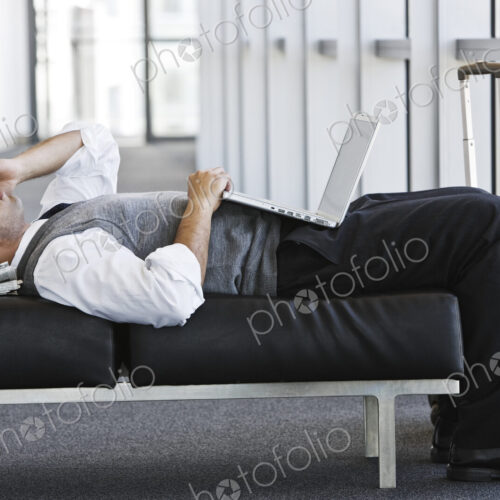Exhausted businessman taking a short break laying on a bench in an office lobby. Exhausted businessman taking a short break laying on a bench in an office lobby.