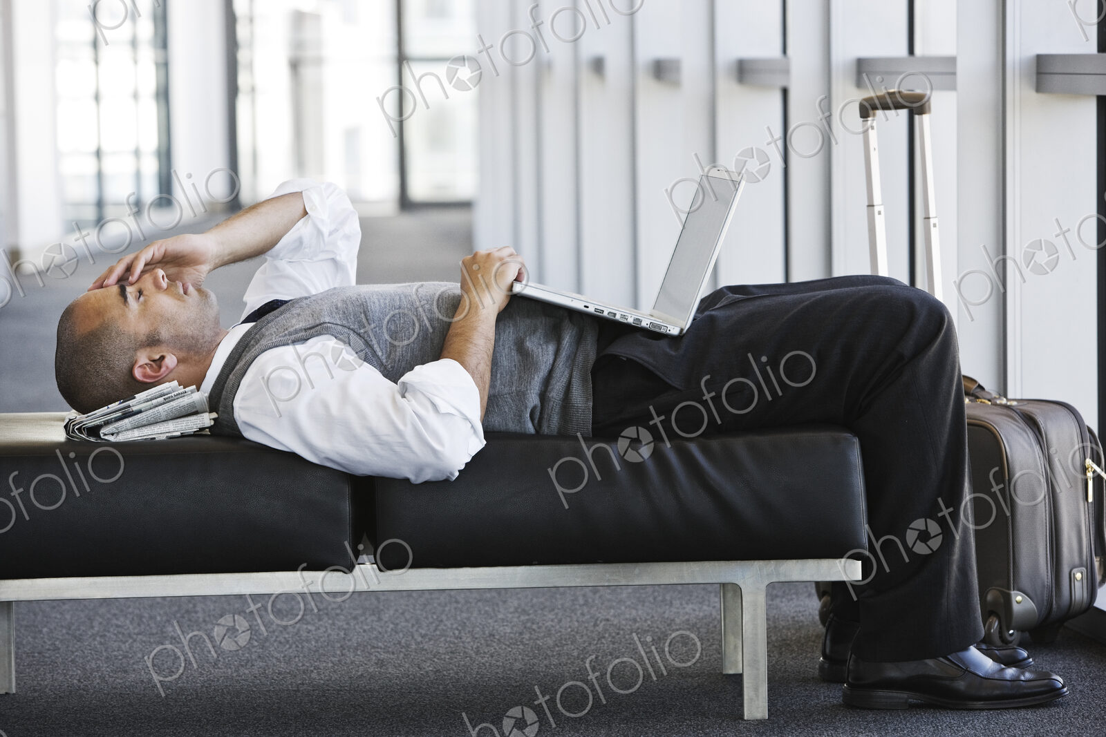 Exhausted businessman taking a short break laying on a bench in an office lobby.