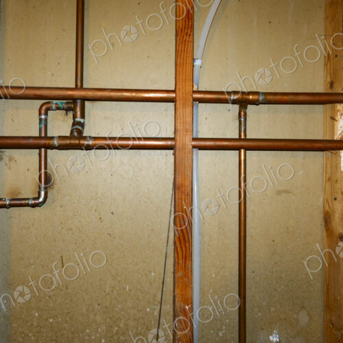 Exposed copper pipes in a network on a wall. Exposed copper pipes in a network on a wall.