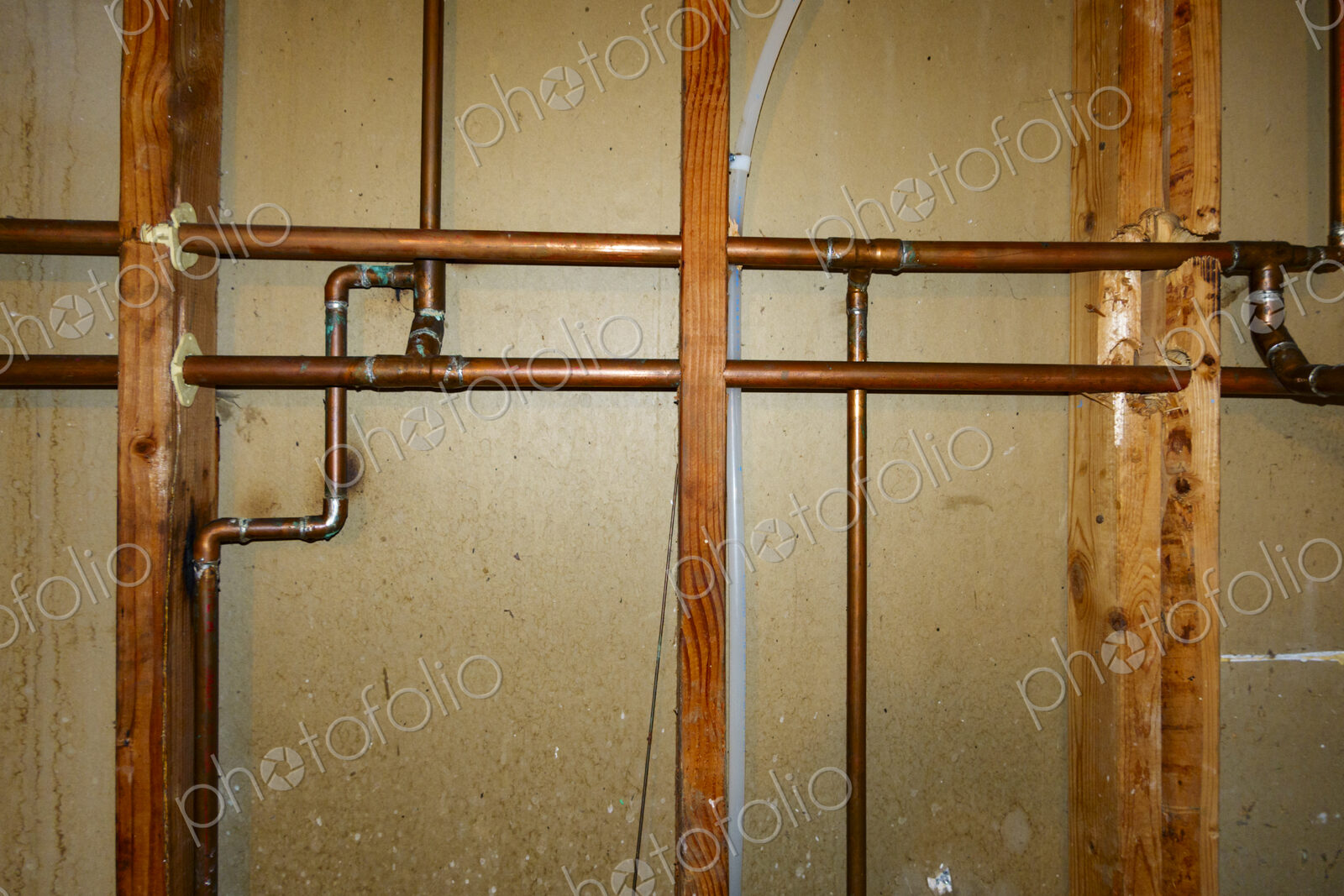 Exposed copper pipes in a network on a wall.