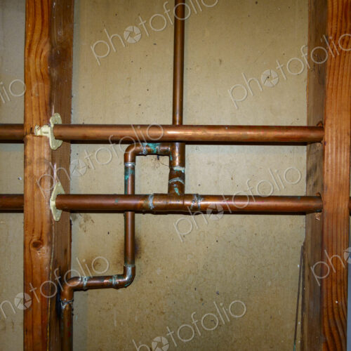 Exposed copper pipes in a network on a wall. Exposed copper pipes in a network on a wall.