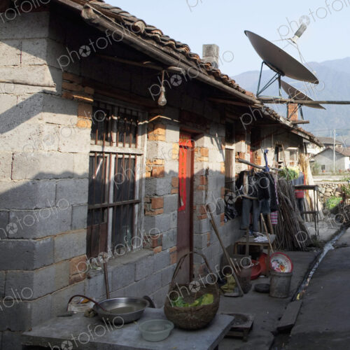 Exterior of rural house in village with satellite dish.