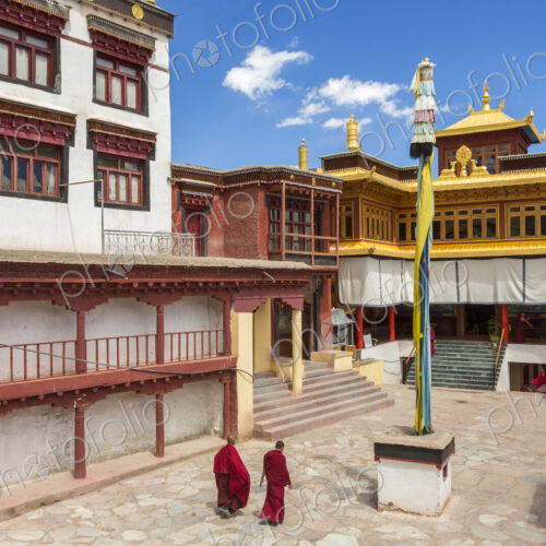 Exterior view of Buddhist monastery with two monks walking across courtyard. Exterior view of Buddhist monastery with two monks walking across courtyard.