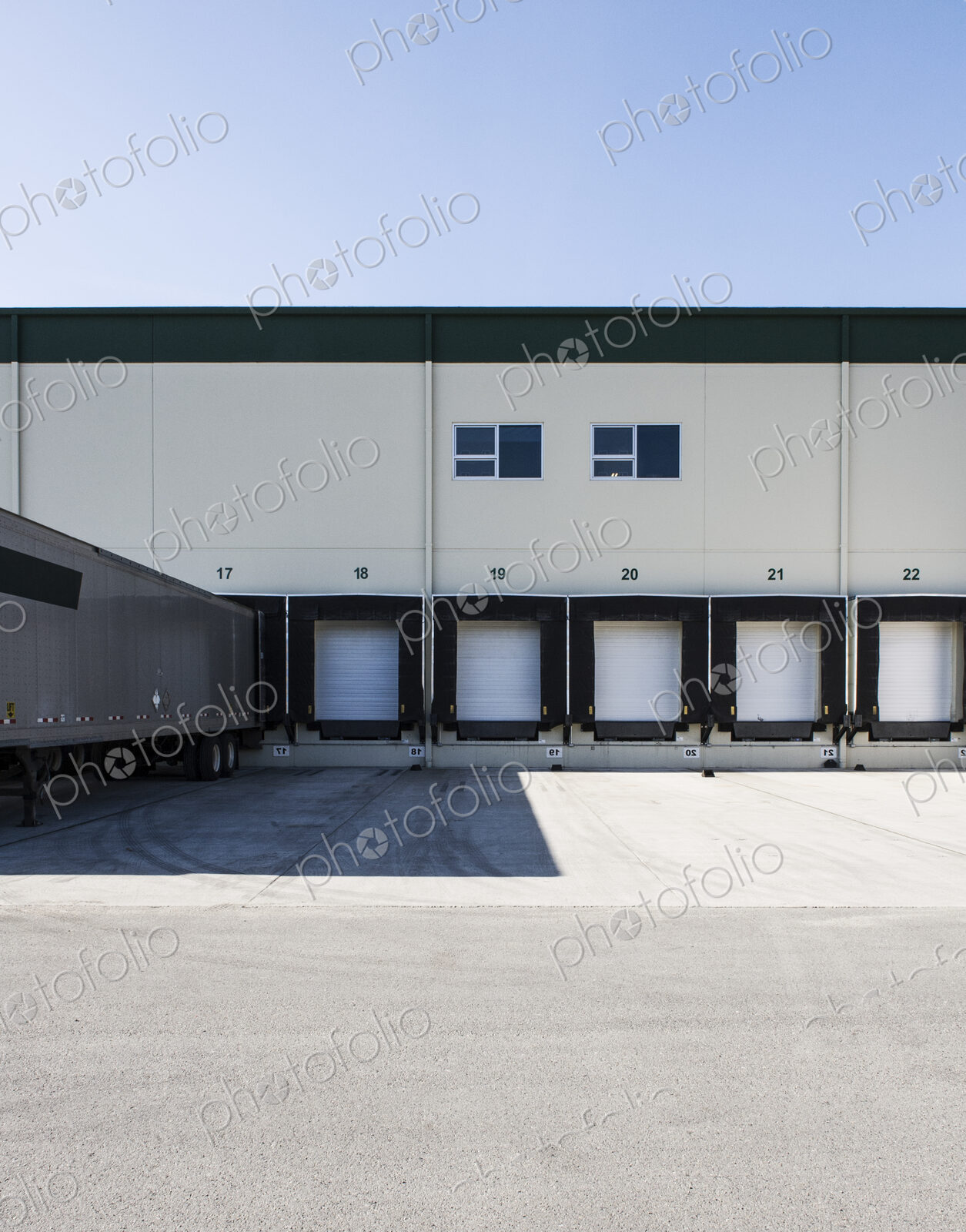 Exterior view of a warehouse loading dock with a truck trailer pulled up to one of the…