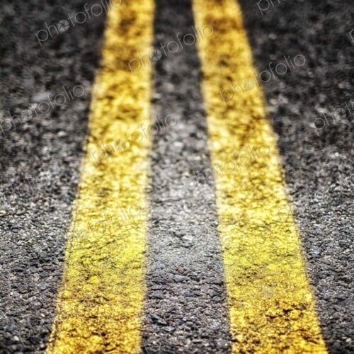 Extreme closeup of double yellow lines, parallel painted lines on the roadway leading away Extreme closeup of double yellow lines, parallel painted lines on the roadway leading away