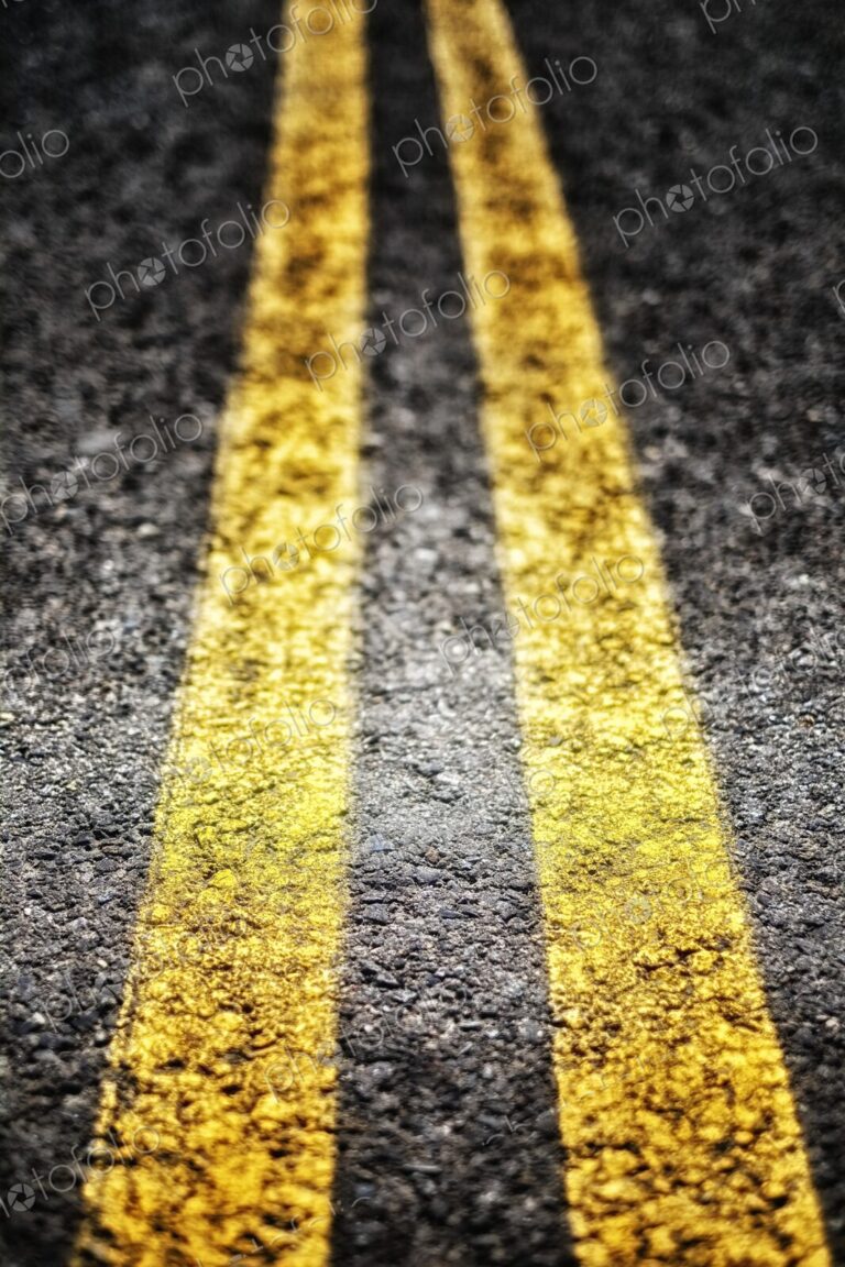 Extreme closeup of double yellow lines, parallel painted lines on the roadway leading away