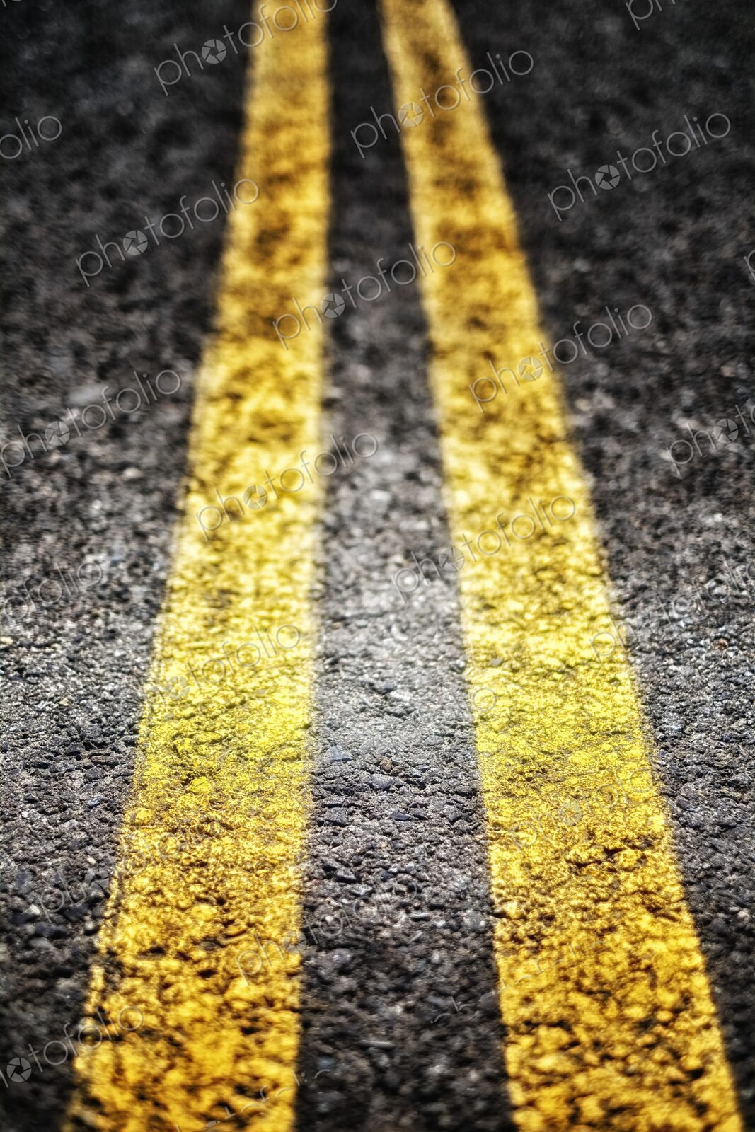 Extreme closeup of double yellow lines, parallel painted lines on the roadway leading away