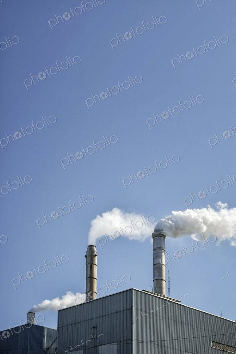 Factory smokestacks against a clear blue sky in Washington state.