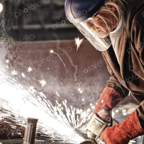 Factory worker grinding a steel edge in a sheet metal factory. Factory worker grinding a steel edge in a sheet metal factory.
