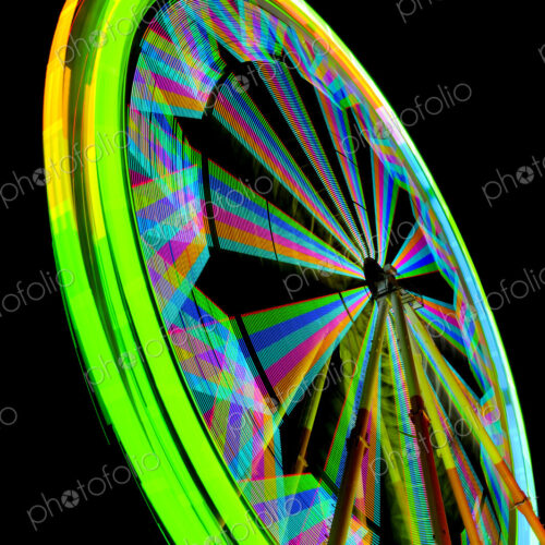 Fairground ferrish wheel with lights in rainbow colours, against a black sky. Fairground ferrish wheel with lights in rainbow colours, against a black sky.