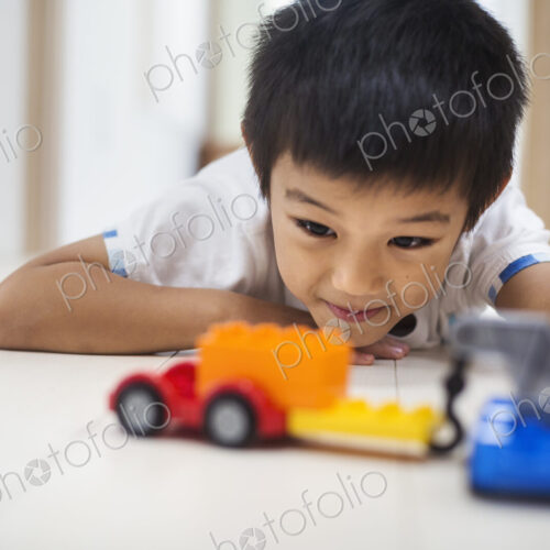 Family home. A boy playing with cars on the floor.