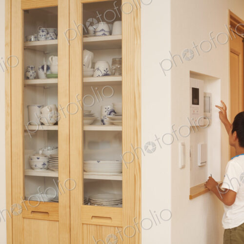 Family home. A boy reaching and looking at a digital display on a wall.