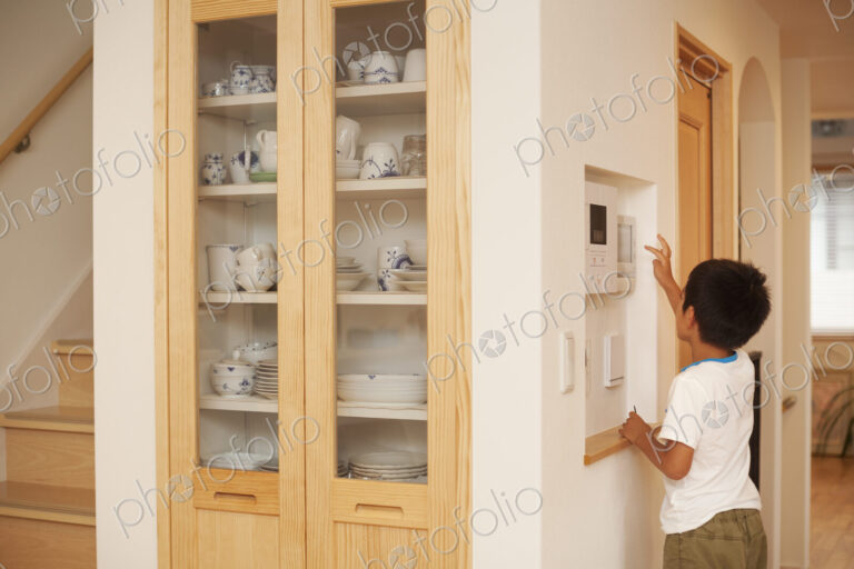 Family home. A boy reaching and looking at a digital display on a wall.