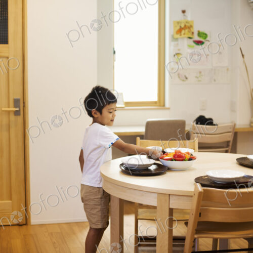 Family home. A boy setting the table for a meal. Family home. A boy setting the table for a meal.