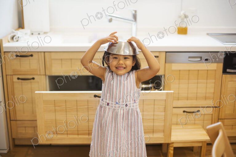 Family home. A child playing, with a metal bowl on her head.