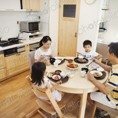 Family home. A family of two adults and two children seated at a meal at home. Family home. A family of two adults and two children seated at a meal at home.