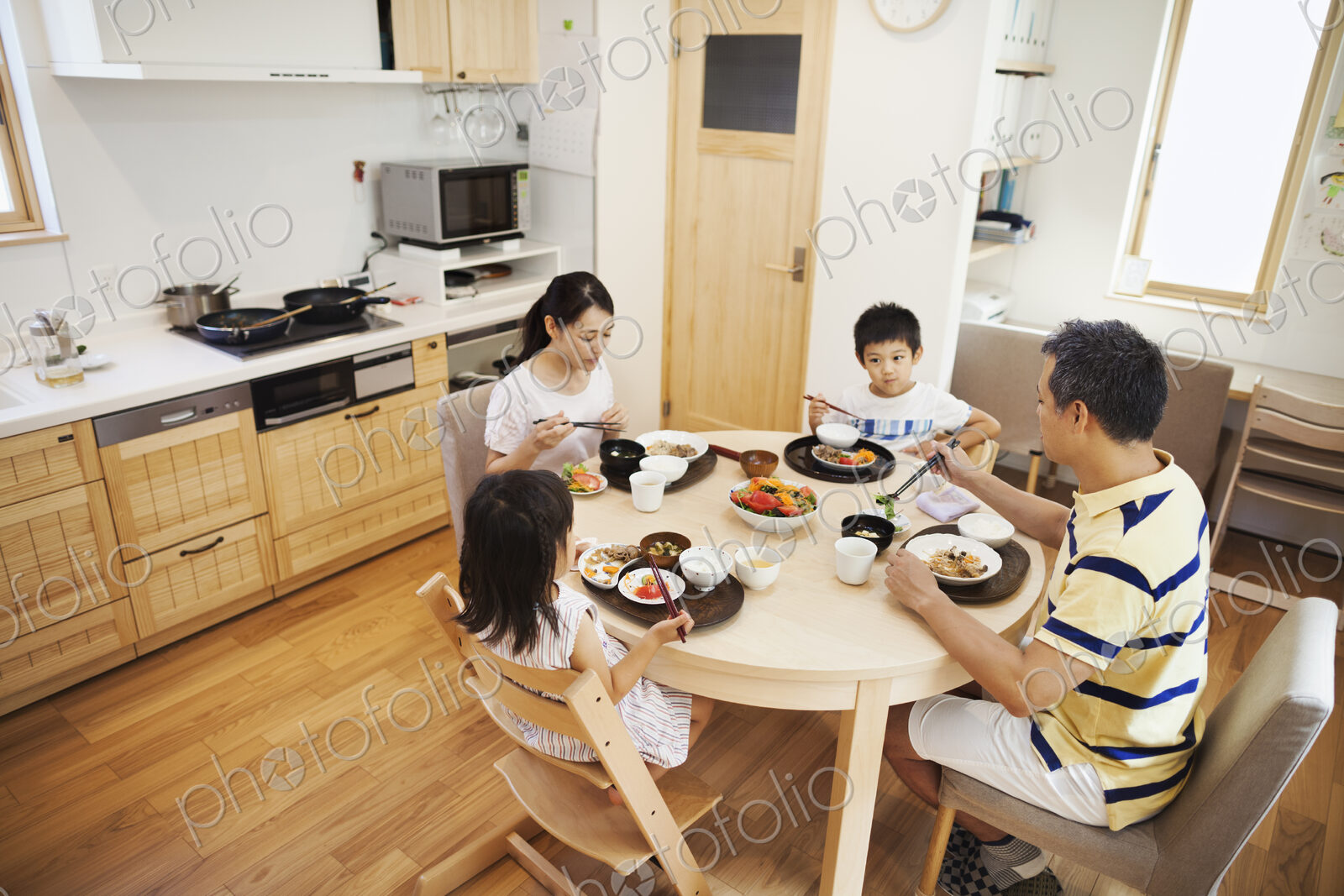 Family home. A family of two adults and two children seated at a meal at home.