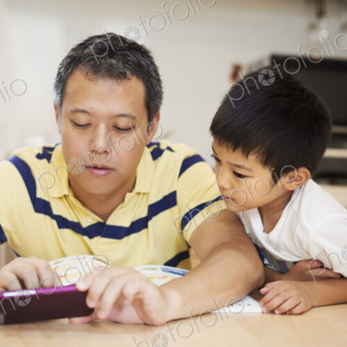 Family home. A man and his son looking at the screen of a smart phone.