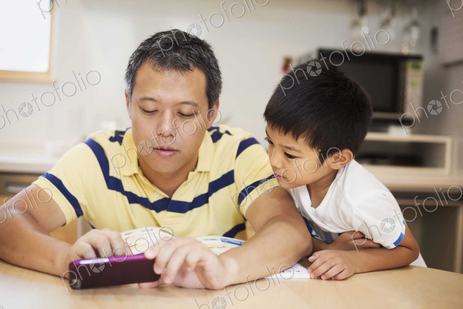 Family home. A man and his son looking at the screen of a smart phone.