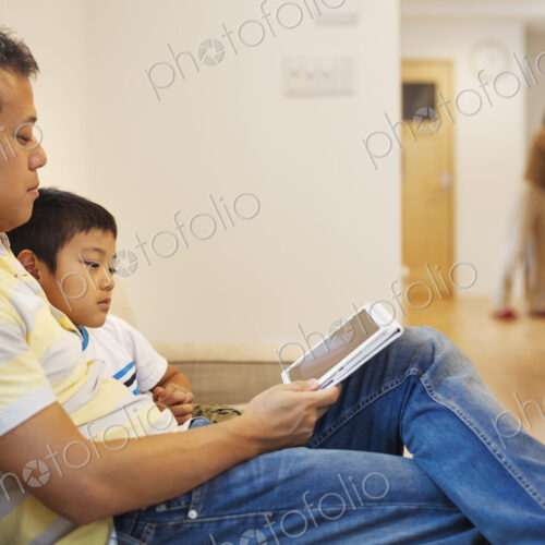 Family home. A man and his son sitting reading a book. Family home. A man and his son sitting reading a book.