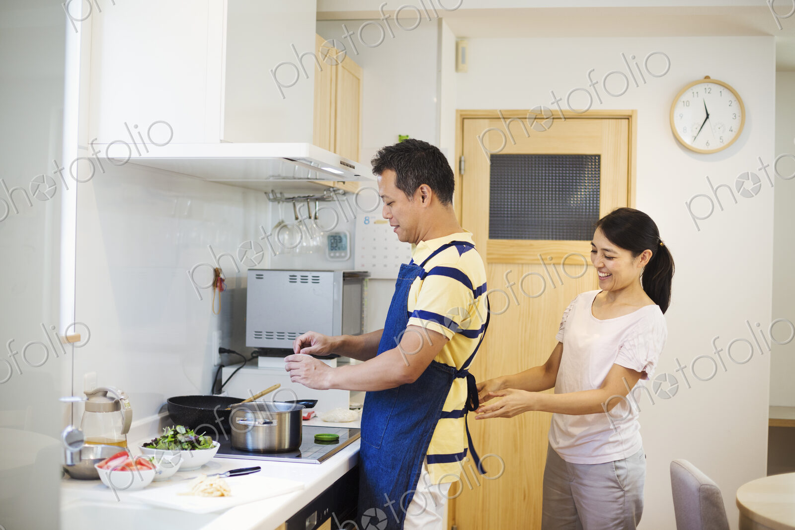 Family home. A man and woman, a wife tying her husband’s apron in their kitchen.