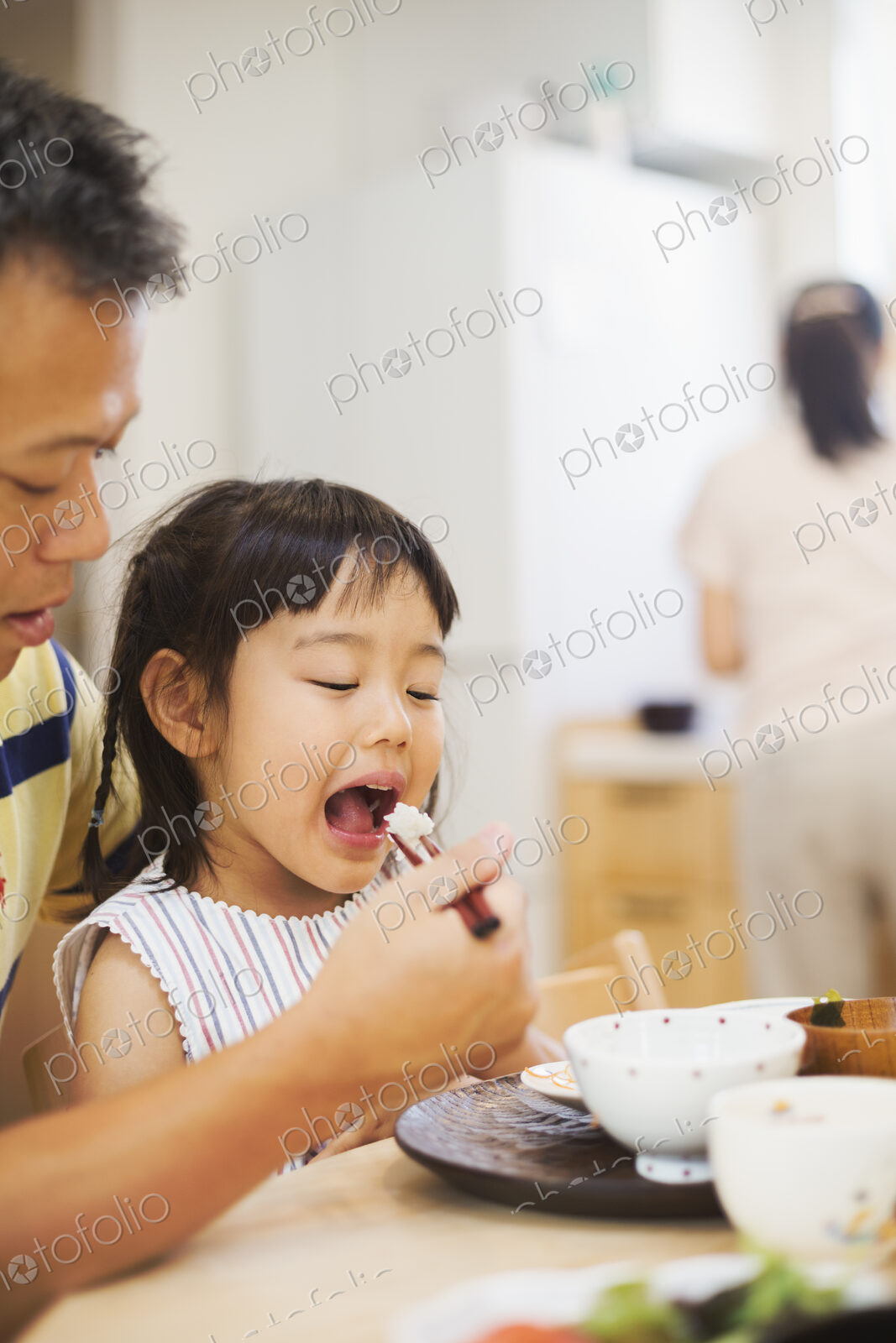 Family home. A man feeding his daughter at a meal.