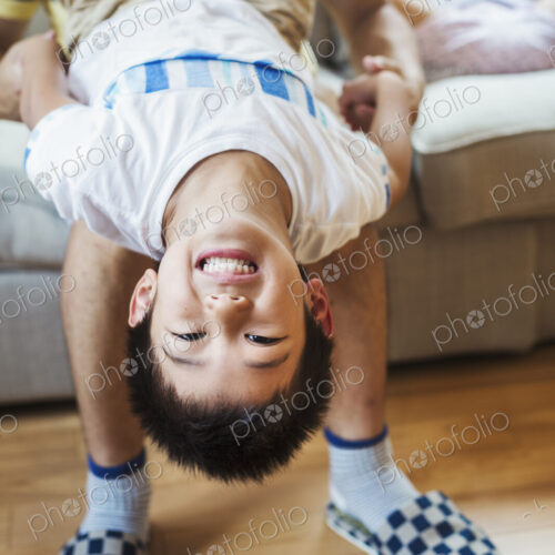 Family home. A man holding his son upside down playing. Family home. A man holding his son upside down playing.