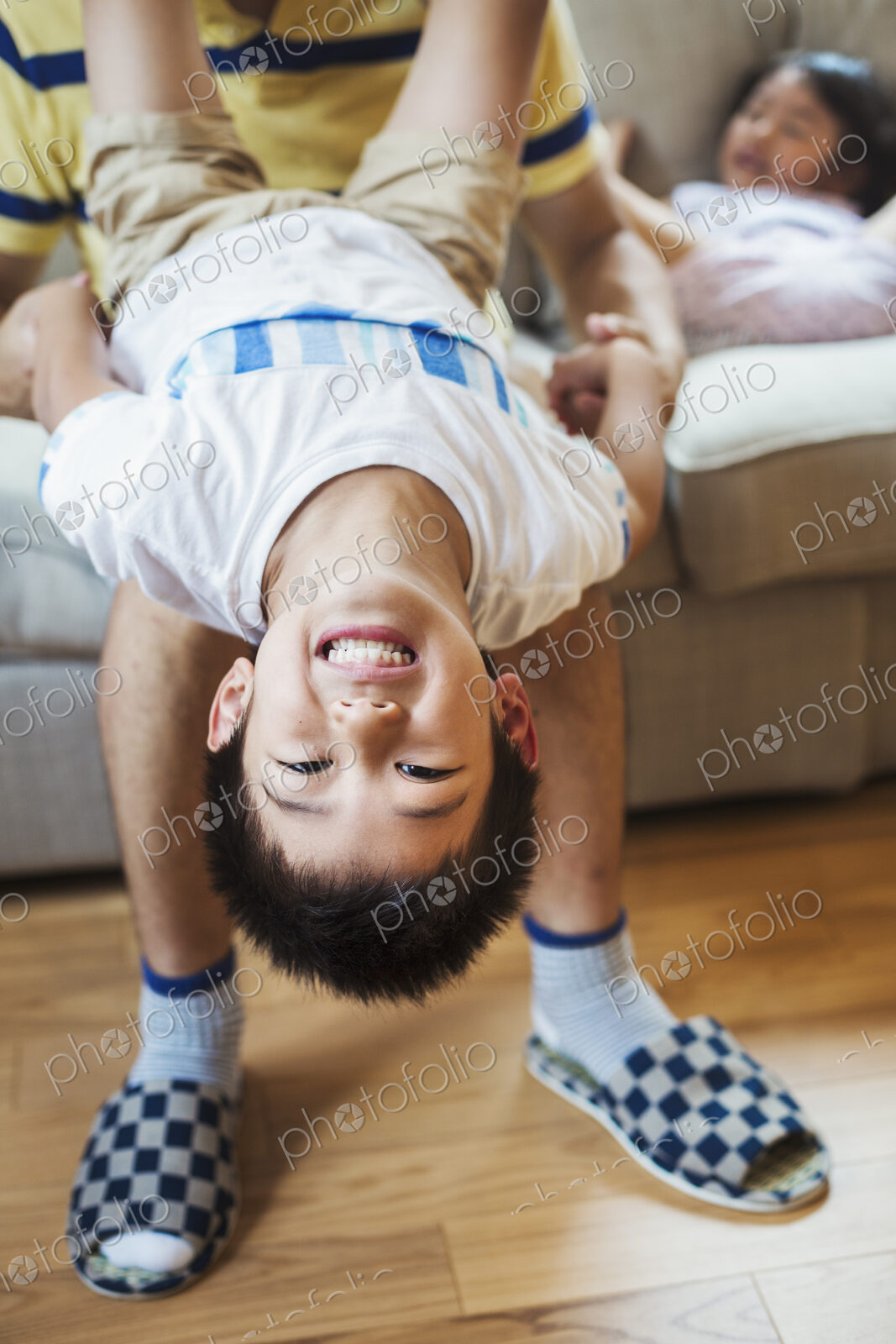 Family home. A man holding his son upside down playing.