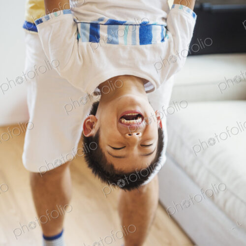 Family home. A man holding his son upside down playing. Family home. A man holding his son upside down playing.