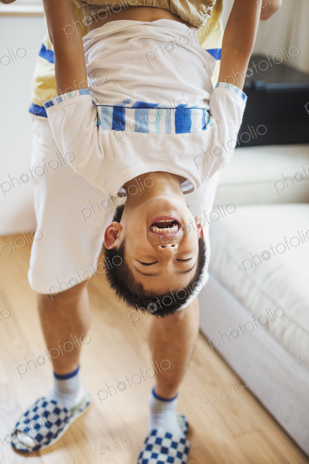 Family home. A man holding his son upside down playing.