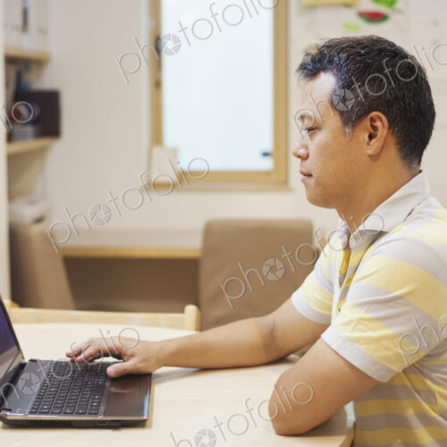 Family home. A man seated using a laptop. Family home. A man seated using a laptop.