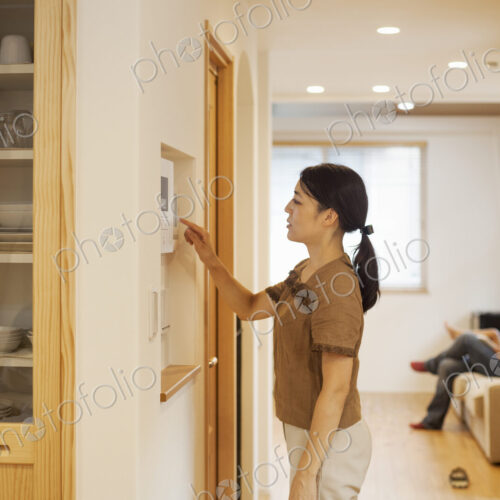 Family home. A woman adjusting the thermostat on a wall in the house.