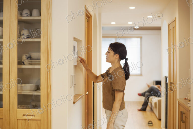 Family home. A woman adjusting the thermostat on a wall in the house.