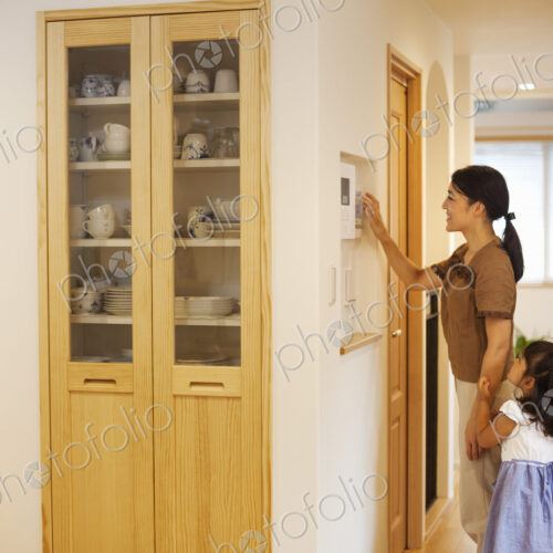 Family home. A woman adjusting the thermostat on a wall in the house. Family home. A woman adjusting the thermostat on a wall in the house.