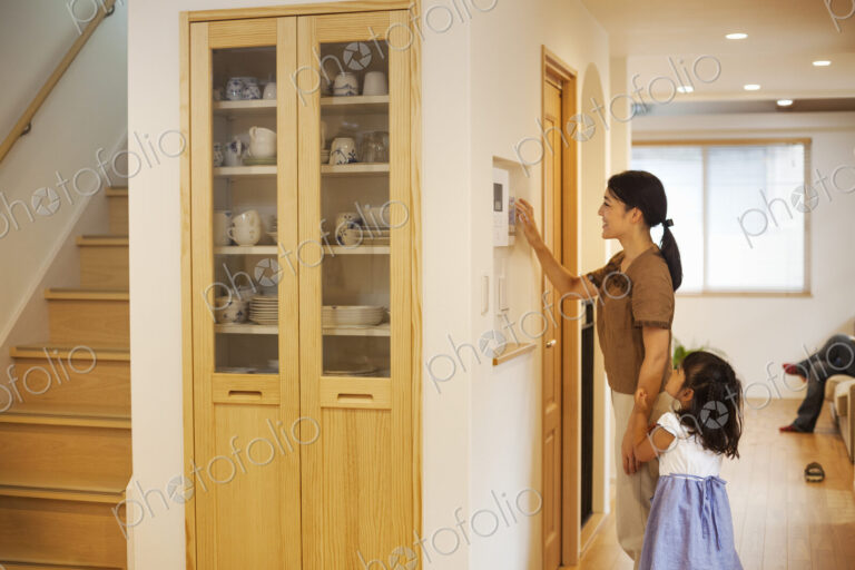 Family home. A woman adjusting the thermostat on a wall in the house.